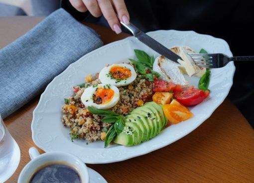 A delicious and healthy breakfast featuring avocado, eggs, and coffee served on a wooden table.