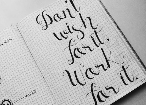 Close-up of motivational calligraphy on grid paper, inspiring message for productivity.